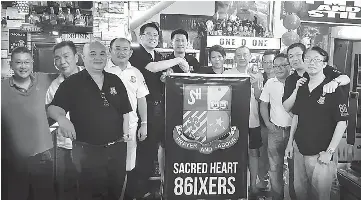  ??  ?? The 86ixers motto, as their president Joseph Lau (fifth from left) hands over the banners for Friday night’s event to Tiong (seventh from left) one of the proprietor­s of 101 Café who is also a former Sacred Heart student.