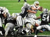  ?? Chris Unger / Getty Images ?? Justin Herbert (with ball) dives into the end zone to give the Chargers the win in overtime.