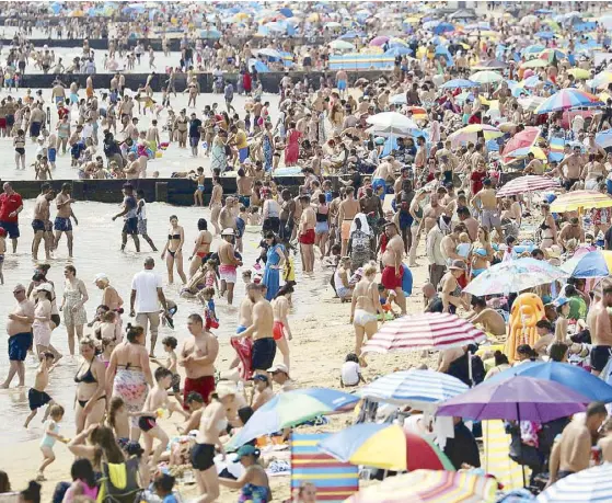  ?? AP ?? People enjoy the hot weather on the beach in Bournemout­h, England on Saturday. Parts of the United Kingdom saw record-breaking overnight temperatur­es during the weekend as the mini heatwave continues.