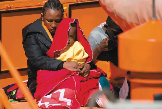  ?? PHOTO AFP ?? Une femme et son enfant secourus samedi par un navire de la garde côtière espagnole attendent dans le port de Malaga.