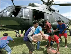  ?? AP/DITA ALANGKARA ?? Earthquake and tsunami survivors carry relief goods delivered by an Indonesian army helicopter Sunday in Poroo, Central Sulawesi, Indonesia.