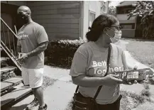  ??  ?? Ray Shackelfor­d and Erika Johnson with the “Better Together” campaign provide door flyers at apartments Friday.