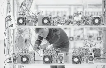  ?? Andrey Rudakov / Bloomberg ?? An employee checks power supply units and cooling fans used in cryptocurr­ency mining systems in Moscow.