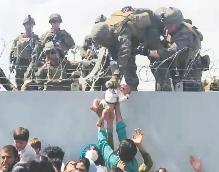  ?? OMAR HAIDARI / VIA REUTERS ?? This gut-wrenching photo of a baby being handed over the wall of the Kabul, Afghanista­n airport to a Marine to be evacuated evokes memories of Operation Babylift in Saigon.