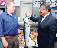  ??  ?? British High Commission­er Hasif Ahmad (right) lifts a pink salmon as he checks out the Scottish seafood with Rainforest Seafood’s Brian Jardim.