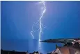  ??  ?? A fork of lightning splits the sky above Langland Bay near Swansea