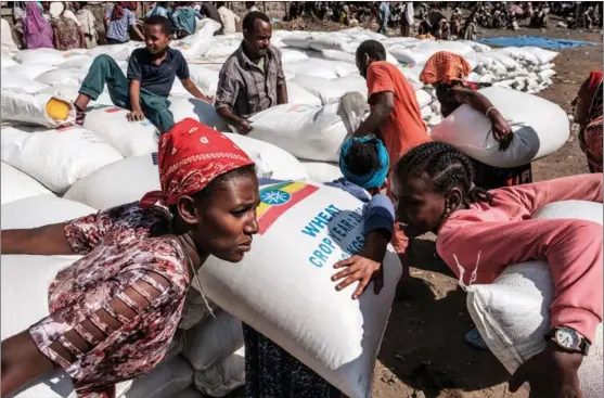  ?? EDUARDO SOTERAS / AFP ?? Women carry sacks of wheat during a distributi­on of food organized by the Ethiopian government in Alamata, Ethiopia, on Dec 11. The country has been hit hard by COVID-19.