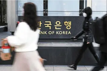  ?? — Bloomberg ?? Cost pressures: People walk in front of the BOK building in Seoul. Inflation remains a major concern for the central bank after it edged up to 5.7% in October.