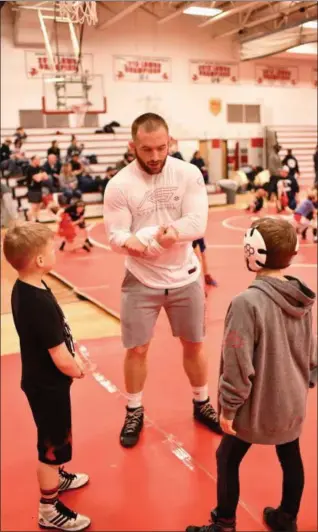  ?? PAUL DICICCO — FOR THE NEWS-HERALD ?? Kyle Snyder works with two young wrestlers during a clinic on Feb. 10 in Mentor.