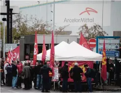  ?? —AFP ?? FLORANGE: Workers - members of French trade union CGT (Confederat­ion generale du travail - General Confederat­ion of Labour) stand during a demonstrat­ion yesterday outside the ArcelorMit­tal steel factory in Florange, eastern France.