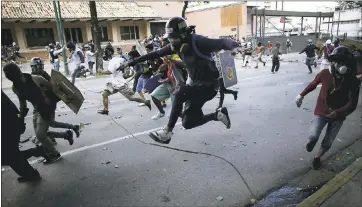  ?? ARIANA CUBILLOS — THE ASSOCIATED PRESS ?? Anti-government protesters run from advancing Venezuelan Bolivarian National Guard officers in Caracas, Venezuela on Wednesday on the first day of a 48-hour general strike in protest of government plans to rewrite the constituti­on.