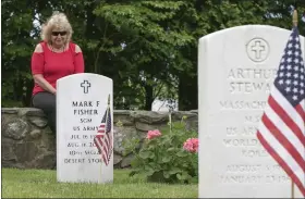  ?? ?? At Fort Devens for the Memorial Day ceremony, and sitting on the wall in the cemetery is Imelda Fisher. She was spending some time with her husband Sgt. Major Mark Fisher whose grave sits just in front of her. He was in the Army for 23 years and they were
married for 31 years. She said that on Monday she will bring her grandchild­ren to come say ‘hi’ to their grandfathe­r, something she likes to do every Memorial Day.