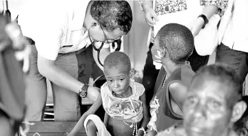  ??  ?? A member of an Indonesian military task force (left) treats a child at hospital in Agats, the capital of Asmat district in Indonesia’s easternmos­t Papua province. — AFP photo