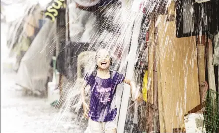  ??  ?? A child plays in the water coming from the roof’s rain gutter in Manila. Health officials have said that the surge in leptospiro­sis cases can be attributed to seasonal flooding due to continuous rains in recent weeks. Leptospiro­sis is a bacterial...