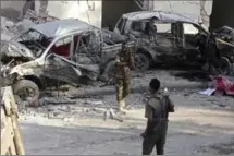  ?? FARAH ABDI WARSAMEH, THE ASSOCIATED PRESS ?? Somali soldiers stand near the wreckage of vehicles in Mogadishu, Somalia, on Sunday after a car bomb detonated Saturday night.