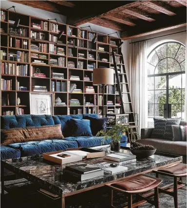  ?? Courtesy photo ?? A wall of custom-made bookcases dominate this family room. Wooden ceiling beams give the room a sense of age.