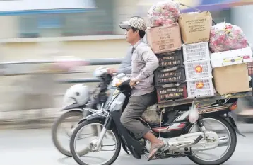  ??  ?? A Cambodian man rides his motorbike loaded with goods along a street in Phnom Penh. Cambodia’s economy is forecast to grow 6.9 per cent next year, compared with a projected 6.8 per cent pace in 2017, despite risks including uncertaint­ies over next...