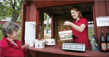  ?? AP PHOTO/CAROLYN KASTER ?? Abby McDonough, 19, a student at Liberty University, right, hands Karen Belle, of Hamilton, Va., her pail of strawberri­es at Wegmeyer Farms in Hamilton, Va. Working at Wegmeyer Farms is one of McDonough’s summer jobs.