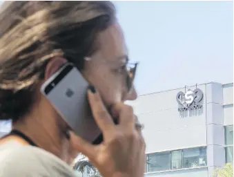  ?? JACK GUEZ/AFP/GETTY IMAGES ?? A woman uses her iPhone in front of the building housing the Israeli NSO group in Herzliya, near Tel Aviv. Undercover efforts to discredit investigat­ions of the company have been discovered.