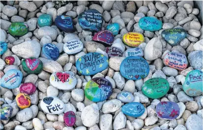  ?? AL DIAZ AP ?? Stones are placed at a memorial outside Marjory Stoneman Douglas High School during the one-year anniversar­y of the school shooting, on Thursday in Parkland, Fla. A year ago on Thursday, 14 students and three staff members were killed when a gunman opened fire at the high school. •