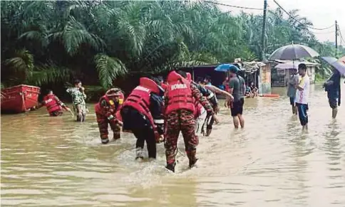  ??  ?? ANGGOTA bomba memindahka­n penduduk yang terjejas akibat banjir kilat di Kampung Pertanian Garinono.