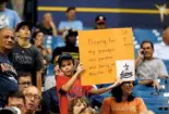  ??  ?? Above: a mother and child waiting to be evacuated from Rockport, Texas. Left: a fan at a baseball game in Florida holding a sign for his storm-affected relatives