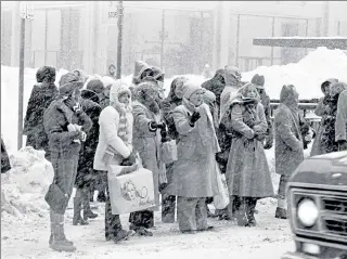  ?? CHARLES KNOBLOCK / AP ?? Homebound Chicago office workers beg for rides from what passing motorists there are on Michigan Avenue on Jan. 15, 1979. Snow began falling in the early afternoon, adding to the 20.5 inches that fell over the weekend. Stranded motorists and abandoned vehicles made commuting nearly impossible.