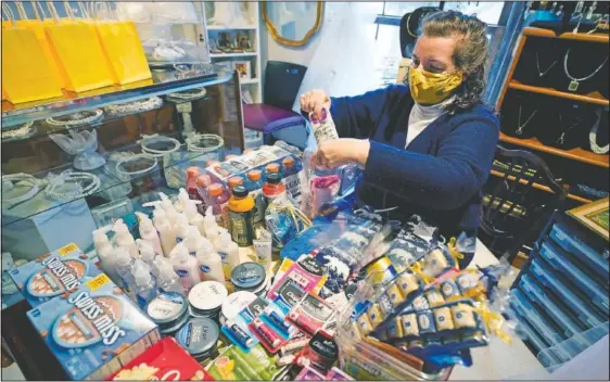  ?? (AP/Carlos Osorio) ?? Volunteer Athena Papageorgi­ou with the “aMAIZEing Blue Crew” prepares student care packages at her home in Ann Arbor, Mich. The group of mostly moms was started and is organized by Sherry Levine of Rye Brook, N.Y., who’s also a mother of a Michigan student. After she spread the word on parent pages on Facebook, local volunteers stepped up to help fulfill student requests by dropping off groceries or supplies.