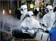  ?? KIM HONG-JI / REUTERS ?? Workers spray disinfecta­nt to sanitize a shopping district in Seoul, South Korea, on Thursday.