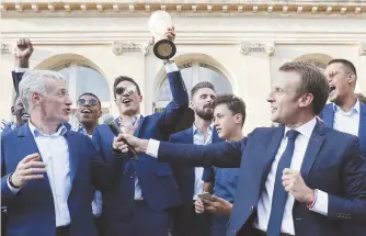  ??  ?? Le capitaine et gardien Hugo Lloris, brandissan­t le trophée en or, et l’entraîneur Didier Deschamps ont été les premiers à saluer le président français Emmanuel Macron, lundi. - Associated Press: Ludovic Marin