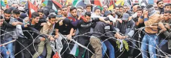  ??  ?? Demonstrat­ors try to remove barbed wire that blocks a road leading to the U. S. Embassy in Aukar, Lebanon, east of Beirut.