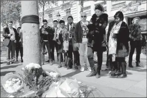  ?? AP/CHRISTOPHE ENA ?? A black ribbon and flowers killed in Thursday’s attack. mark the spot on the Champs-Elysees where a Paris police officer was