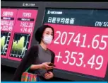  ??  ?? TOKYO: A woman walks past an electronic quotation board displaying share prices of the Tokyo Stock Exchange in Tokyo. Japan will compile a new $1.1 trillion stimulus package to stop the coronaviru­s pandemic pushing the world’s third-largest economy deeper into recession. – AFP