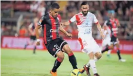  ?? JOHN DURÁN ?? Róger Rojas cubre la pelota ante la marca de José Garro en el juego entre Alajuelens­e y Santos, del pasado miércoles.
