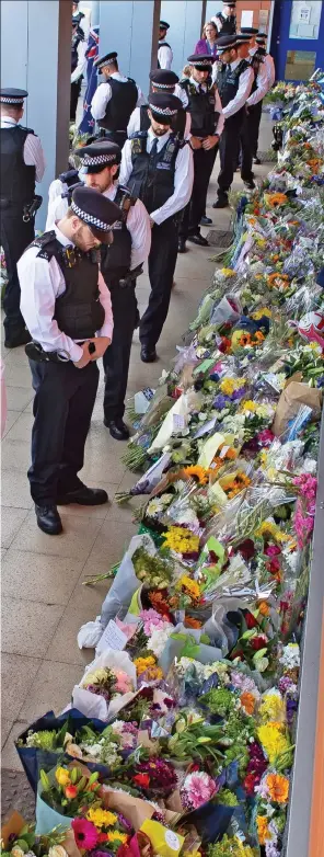  ??  ?? Respect: Colleagues look at flowers placed for Sgt Ratana yesterday