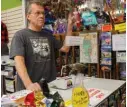  ??  ?? Shop manager of Mt Rushmore T-Shirts, Todd Wicks, speaks during an interview with AFP next to a bottle of hand sanitizer and signs with informatio­n about COVID-19.