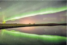  ?? ?? The sky at night: an aurora reflected on tranquil water in Keflavik, south-west Iceland