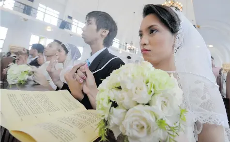  ?? JAY DIRECTO/Getty Images files ?? Couples attend a mass wedding at a university chapel in the Philippine­s. Church weddings are an important part of tradition in the country, where more than
80 per cent are Roman Catholics, a legacy of Spanish rule. However, divorces are forbidden,...