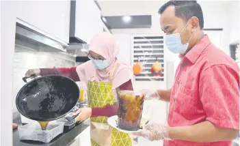  ?? — Bernama photo ?? Muhd Syafik and Nor Hafsah pouring the finished grass jelly into containers.