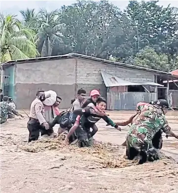  ??  ?? RESCUE: Soldiers and police help residents in flooded East Nusa Tenggara, Indonesia.