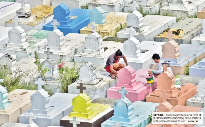  ?? MACKY LIM ?? REPAINT. Two men repaint a colorful tomb at the Roman Catholic Cemetery before relatives of the deceased arrive to visit.