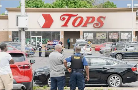  ?? John Normile / TNS ?? Police Saturday cordon off the parking lot of the Tops Friendly Market in Buffalo where 10 people were slain.