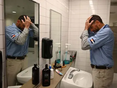  ?? ?? Coach Norvell puts on hair gel after spending a few minutes in the steam sauna and taking a cold shower before heading out for morning practice at Canvas Stadium.