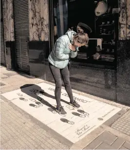  ?? ANITA POUCHARD SERRA For The Washington Post ?? A woman tries to follow the tango steps printed on the ground outside Confitería La Ideal.