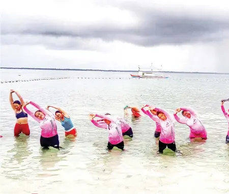  ?? CONTRIBUTE­D FOTO/CEBU PINK PADDLERS ?? DISCIPLINE AND ENDURANCE. Just off Mactan Newtown in Lapu-Lapu City, the Cebu Pink Paddlers stretch ahead of the day’s training drills. Paddling is a whole-body workout that requires core work, leg power and upper-body strength.