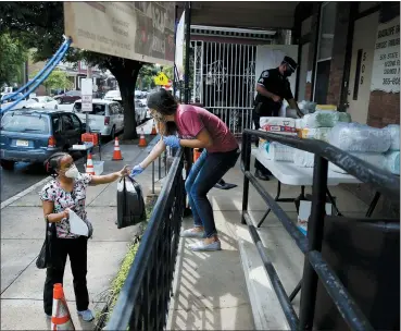  ?? MATT SLOCUM — THE ASSOCIATED PRESS ?? Lourdes Sherby, center, with Guadalupe Family Services, hands diapers to Louisa Peralta in Camden, N.J. “I think we’re received a lot better than we used to be,” said Sgt. Dekel Levy, 41, as he helped hand out diapers to a steady stream of young mothers Thursday afternoon at Guadalupe Family Service.