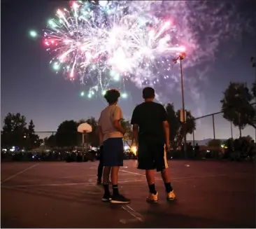  ?? PHOTO BY TREVOR STAMP ?? Youths watch La Puente's fireworks display from a basketball court at La Puente City Park on July 3, 2018. La Puente will not showcase fireworks this year, going instead with a laser light show after its pyrotechni­cs contractor, Exposhows Inc. of Santa Monica, was placed under investigat­ion by the State Fire Marshal. Lynwood, Lancaster and Palmdale also canceled shows.