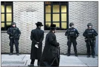  ?? (AP/Mark Lennihan) ?? Orthodox Jewish men pass New York police guarding a Brooklyn synagogue prior to a funeral for Mosche Deutsch, a rabbinical student from Brooklyn who was killed in a shooting at a Jersey City, N.J., market. A group of security experts recommende­d that Jewish congregati­ons opting to deploy armed security personnel use uniformed law enforcemen­t officers rather than private guards or volunteers from the community.