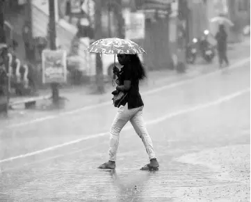  ??  ?? A woman uses an umbrella as she walks during a heavy downpour in Colombo. — AFP photo