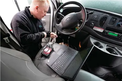  ?? The Associated Press ?? ■ Brian Hohmann, mechanic and owner of Accurate Automotive in Burlington, Mass., attaches a diagnostic­s scan tool, center left, to a vehicle and a laptop computer, below, on Feb. 1 in Burlington. The diagnostic­s scan tool sends informatio­n from the vehicle’s computer to the laptop so a mechanic can view informatio­n about the vehicle’s performanc­e. Hohmann said most independen­t shops are perfectly capable of competing with dealership­s on both repair skills and price as long as they have the informatio­n and software access they need.